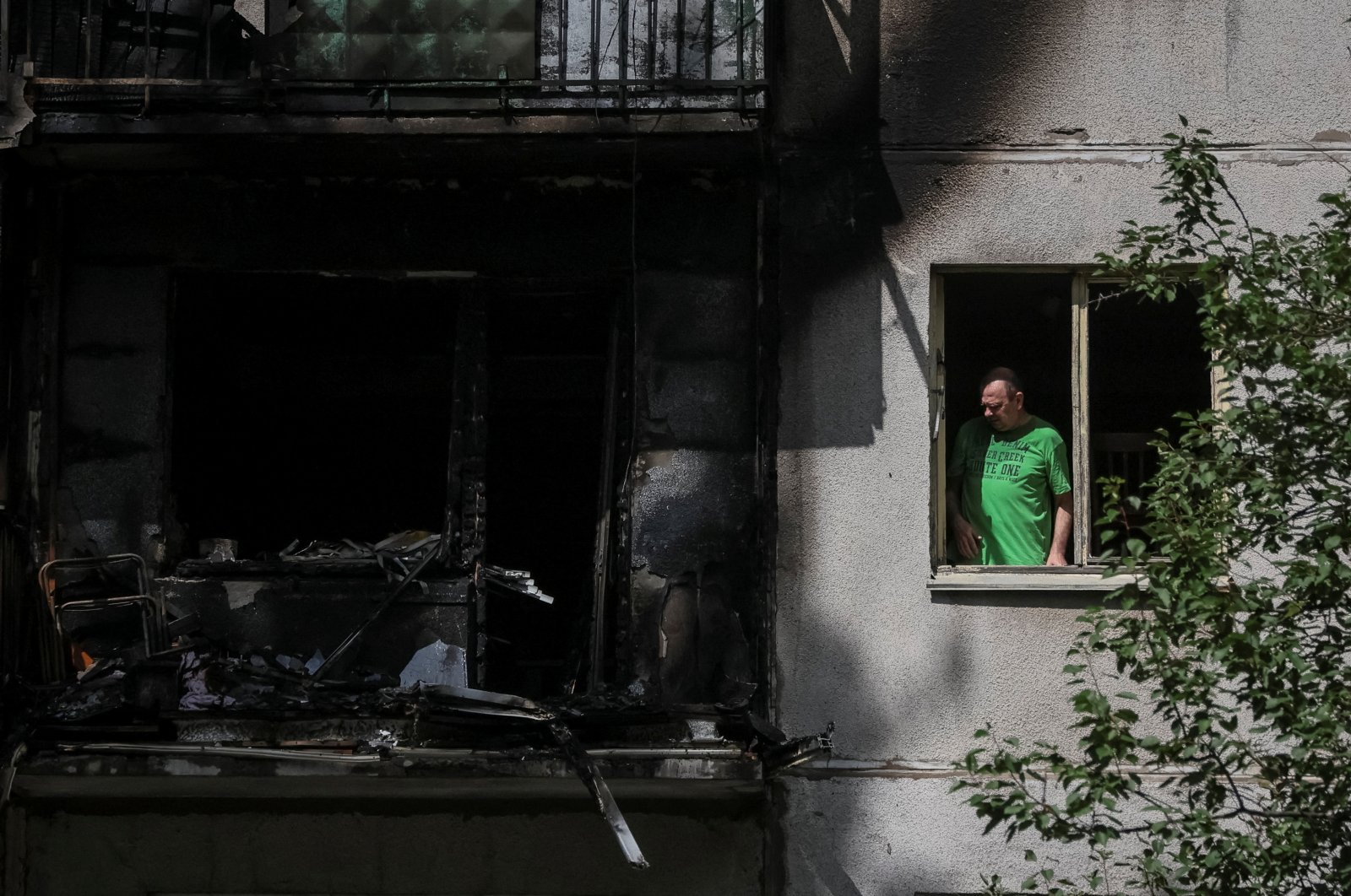 A local resident looks out through a broken window in his flat in a residential building damaged by a Russian military strike in Kramatorsk, Donetsk region, Ukraine, July 19, 2022. (Reuters Photo)