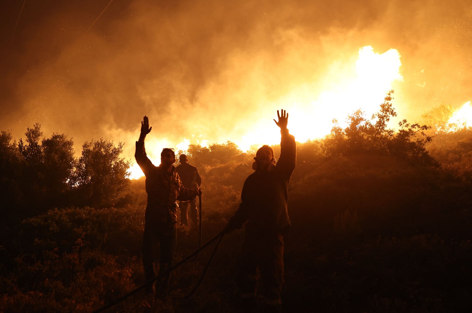 Firefighters gesture as they work to extinguish a wildfire in Drafi agglomeration, north of Athens, Greece, July 19, 2022. (AFP Photo)