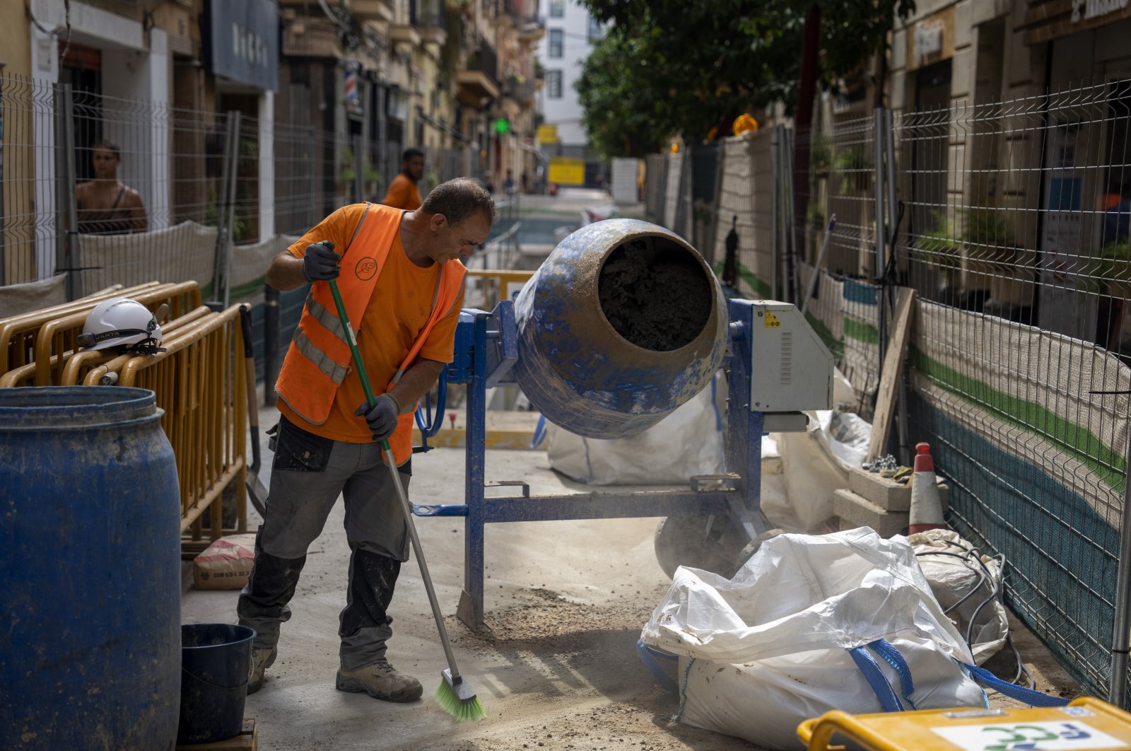 A construction worker cleans the pavement while rehabilitating a street in Barcelona, Spain, Wednesday, July 20, 2022. (AP Photo)
