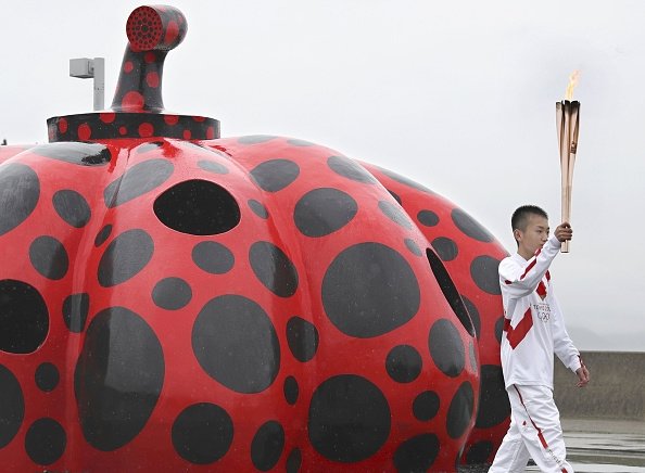 A Tokyo Olympic Torch Relay runner passes a work by internationally acclaimed Japanese artist Yayoi Kusama in Naoshima, Seto Inland Sea, western Japan's Kagawa Prefecture.  (Getty Images)