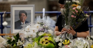 A mourner offers flowers next to a picture of late former Japanese Prime Minister Shinzo Abe, who was shot while campaigning for a parliamentary election, on the day to mark a week after his assassination at the Liberal Democratic Party headquarters, in Tokyo, Japan, July 15, 2022. (Reuters Photo)