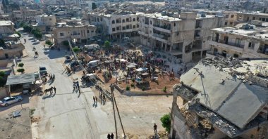 An aerial picture shows a crowd at a fair set up near damaged buildings in the Syrian town of Binnish in the northwestern opposition-held province of Idlib, Syria, July 9, 2022. (AFP Photo)