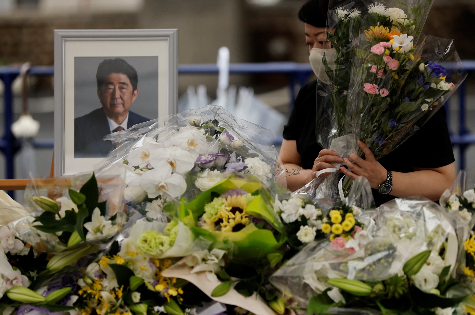 A mourner offers flowers next to a picture of late former Japanese Prime Minister Shinzo Abe, who was shot while campaigning for a parliamentary election, on the day to mark a week after his assassination at the Liberal Democratic Party headquarters, in Tokyo, Japan, July 15, 2022. (Reuters Photo)