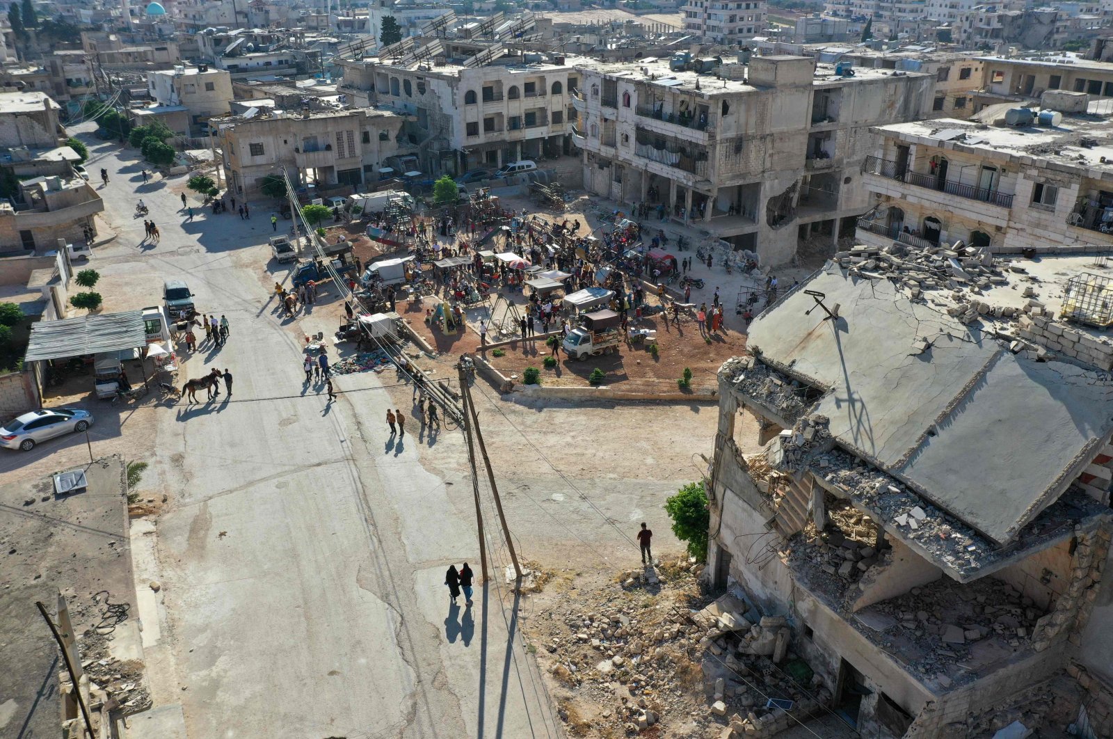 An aerial picture shows a crowd at a fair set up near damaged buildings in the Syrian town of Binnish in the northwestern opposition-held province of Idlib, Syria, July 9, 2022. (AFP Photo)