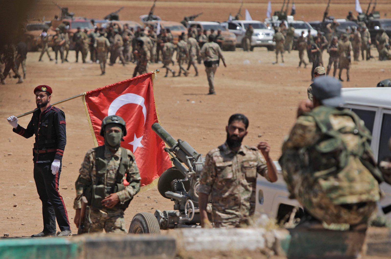 A man carries a Turkish national flag as Turkey-backed Syrian fighters gather along the frontlines opposite YPG forces near the town of Dadat north of Manbij in Syria's northern Aleppo province, on July 5, 2022. (AFP)