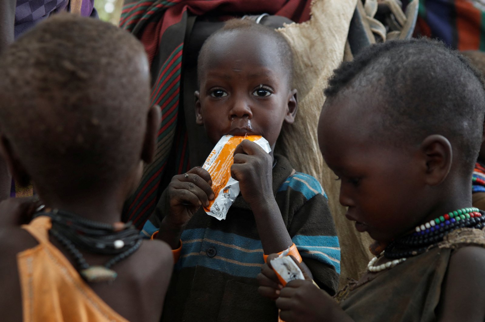 Turkana children eat food supplements given by Save the Children organisation during an outreach program in the drought hit Lorengo village, Turkana, Kenya, July 19 2022. (Reuters Photo)