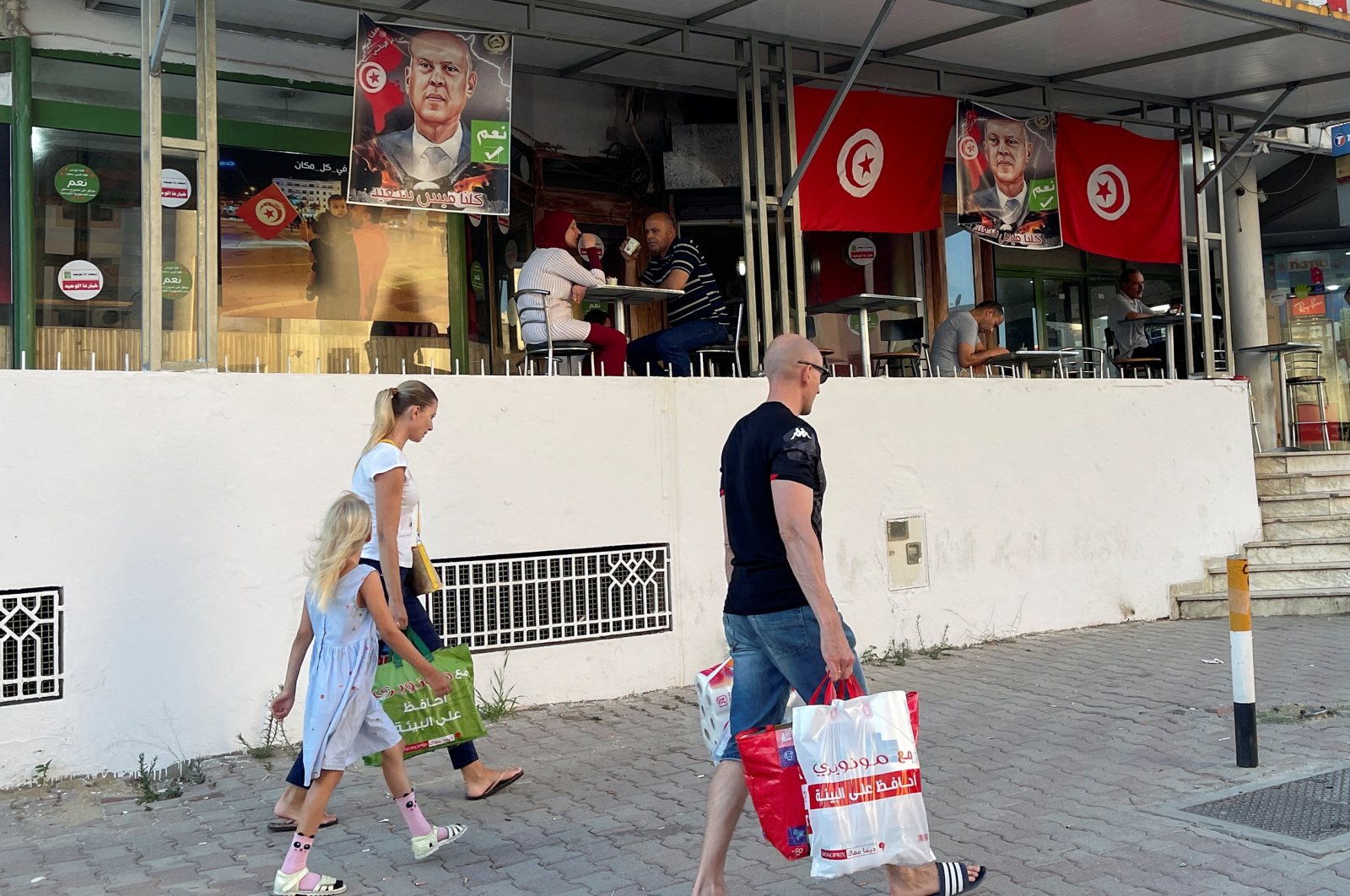 People walk past a cafe decorated with Tunisian flags and pictures of Tunisia&#039;s President Kais Saied, ahead of an upcoming referendum on a new constitution, in Tunis, Tunisia, July 15, 2022. (Reuters Photo)
