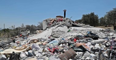 A Syrian youth gestures above debris following a Russian airstrike on the outskirts of the opposition-held city of Jisr al-Shughur in Syria's northwestern province of Idlib, July 22, 2022. (AFP Photo)