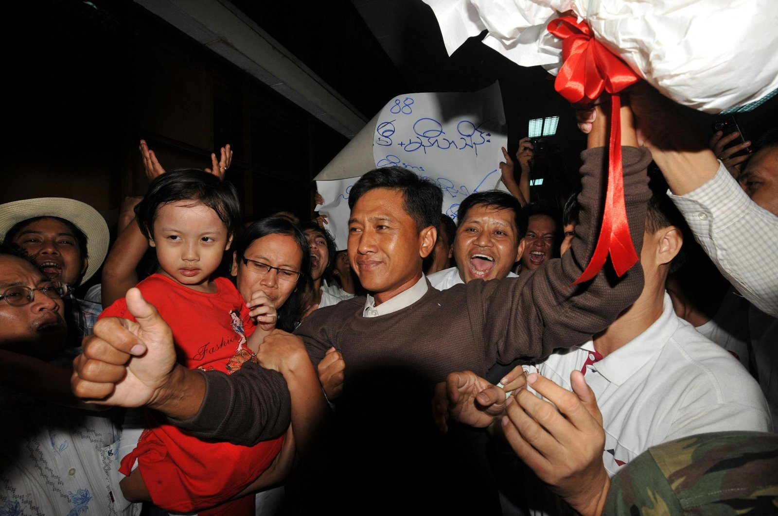Kyaw Min Yu (C), known as Jimmy, and his wife Ni Lar Thein (L) holding her child, both members of the 88 Generation student group, celebrate upon their arrival at Yangon international airport following their release from detention, Myanmar, Jan. 13, 2012. (AFP File Photo)