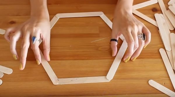 Laying out the popsicle sticks to form hexagon shelves. (Pinterest / via dekordiyon.com)