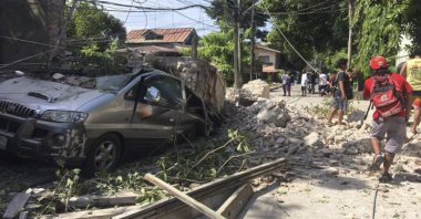A vehicle is damaged by a collapsing wall after a strong earthquake hit Ilocos Sur province, Philippines, July 27, 2022. (Philippine Red Cross via AP)