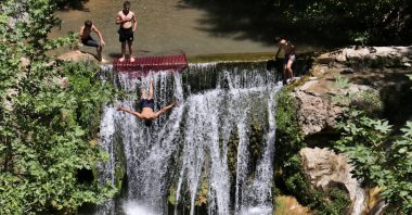 People jump from a waterfall in Osmaniye, southern Turkey, July 24, 2022. (AA PHOTO)