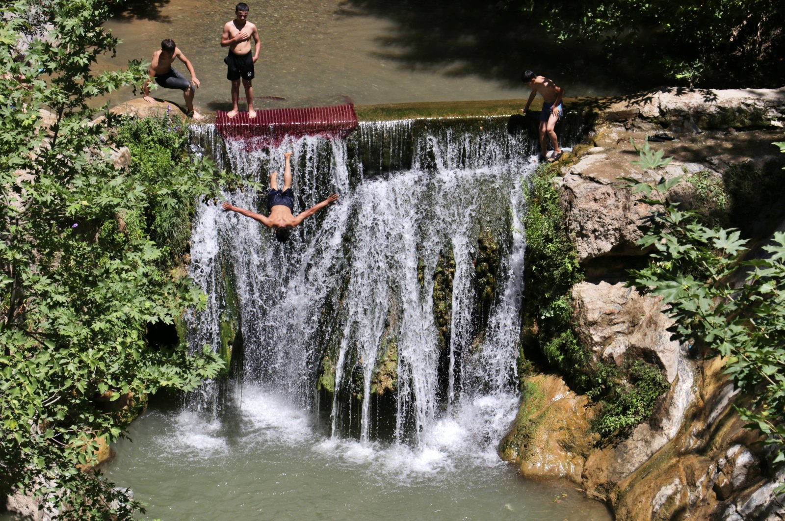 People jump from a waterfall in Osmaniye, southern Turkey, July 24, 2022. (AA PHOTO)