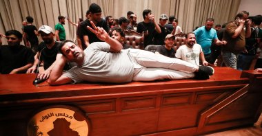 A supporter of Iraqi cleric Muqtada al-Sadr lies on the desk of the speaker of the Iraqi parliament, as demonstrators gather inside the Iraqi parliament, in the high-security Green Zone, Baghdad, Iraq, July 27, 2022. (AFP Photo)