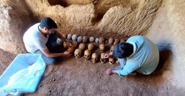 Experts examine skulls found in the grave, in Adıyaman, eastern Turkey, July 28, 2022. (İHA PHOTO)