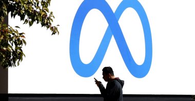 A pedestrian walks in front of a new logo and the name 'Meta' on the sign in front of Facebook headquarters in Menlo Park, California, Oct. 28, 2021. (Photo by JUSTIN SULLIVAN / GETTY IMAGES NORTH AMERICA / AFP)