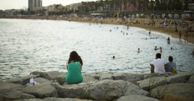 A woman sits by the beach in Barcelona, Spain, Thursday, July 28, 2022. Spain government's Equality Ministry launched a summer campaign Thursday encouraging women to reject "stereotypes" and "aesthetical violence," a reference to social pressure some women feel to conform to beauty ideals. (AP Photo)