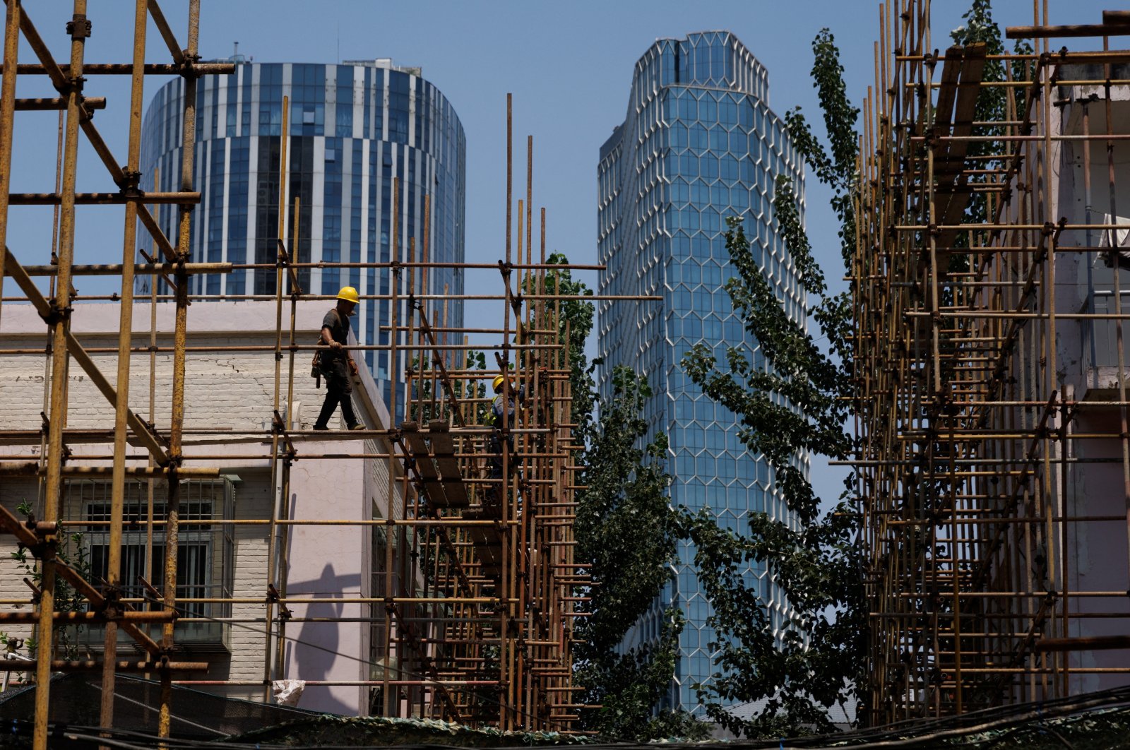 A worker walks on a scaffolding at a construction site of an apartment building under refurbishment in Beijing, China, July 20, 2022. (Reuters Photo)