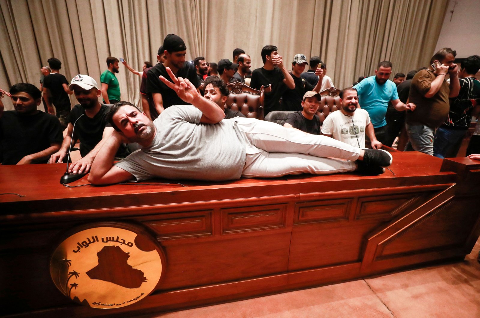 A supporter of Iraqi cleric Muqtada al-Sadr lies on the desk of the speaker of the Iraqi parliament, as demonstrators gather inside the Iraqi parliament, in the high-security Green Zone, Baghdad, Iraq, July 27, 2022. (AFP Photo)