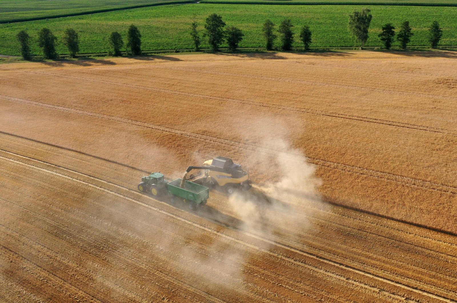 An aerial view shows farmers using combine harvesters and tractors to harvest grain from their fields near the small village of Alling, southern Germany, July 18, 2022. (AFP Photo)