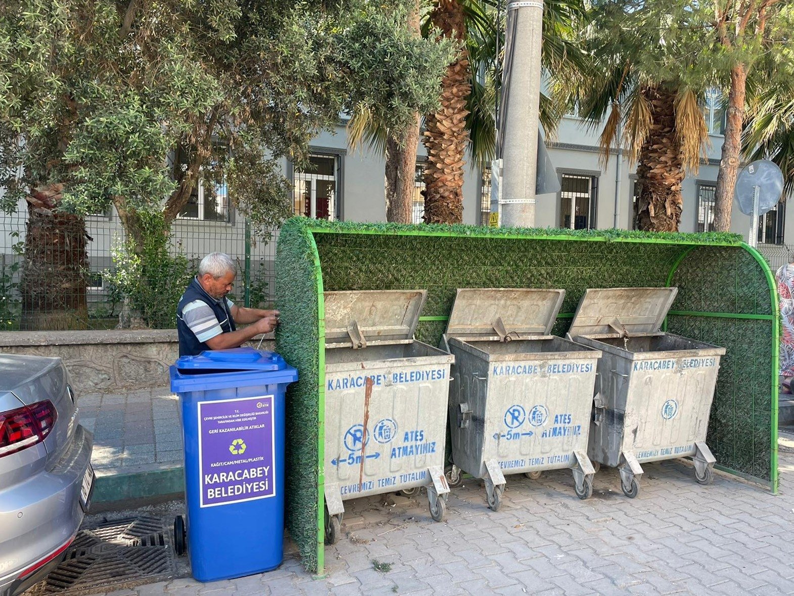 A worker installs a recycling bin next to old garbage dumpsters in the Karacabey district, in Bursa, northwestern Turkey, July 6, 2022. (İHA PHOTO)