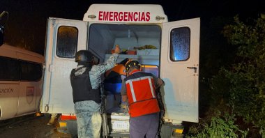 A member of the National Guard uses a torch to help a paramedic giving first aid to a migrant injured inside an ambulance, in the town of Acayucan, in Veracruz state, Mexico, July 27, 2022. (Reuters Photo)