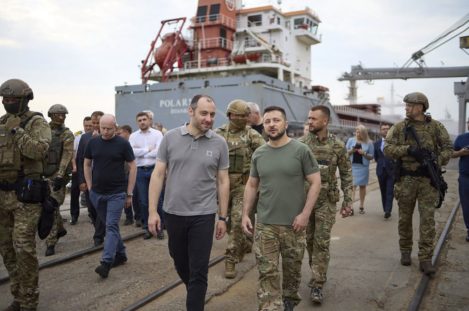 Ukrainian President Volodymyr Zelenskyy (C) surrounded by ambassadors of different countries and U.N. officials, visits a port in Chernomork during the loading of grain on a Turkish ship, background, close to Odessa, Ukraine, July 29, 2022. (Ukrainian Presidential Press Office via AP)
