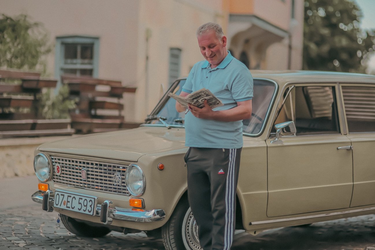Ömer Faruk Yılmaz stands with an original user manual in front of the Murat 124 model classic car that he restored in memory of his late father, Antalya, Turkey, July 11, 2022. (AA Photo)