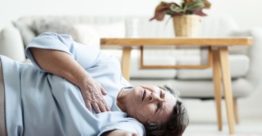 An elderly woman suffering a heart attack lying on the floor. (Shutterstock Photo)