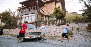 Local children take photos in front of Ömer Faruk Yılmaz&#039;s authentically restored Murat 124 model classic car, the Turkish-built version of Fiat&#039;s 124, Antalya, Turkey, July 11, 2022. (AA Photo)