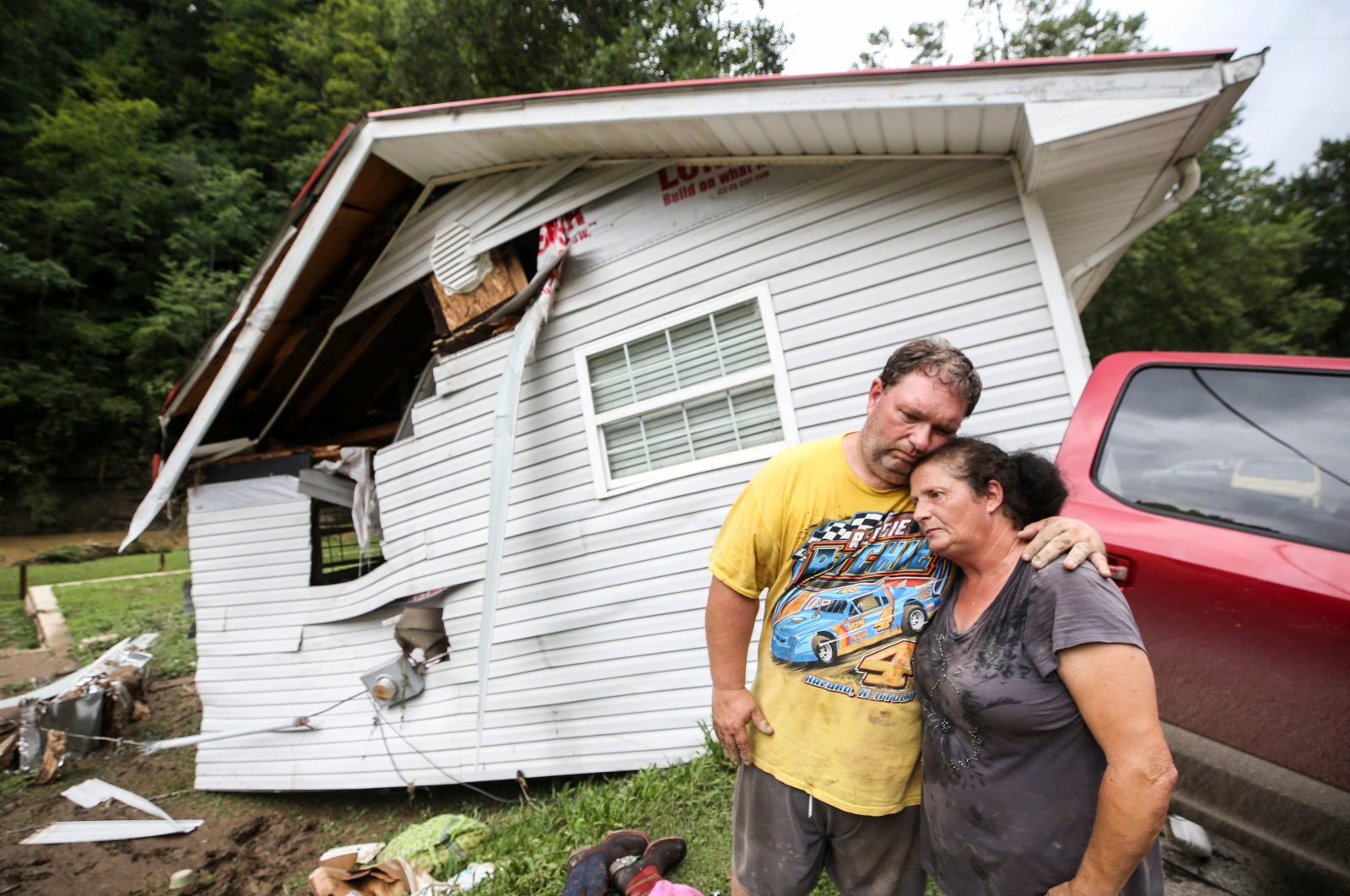 Reggie Ritchie comforts his wife Della as they pause while clearing out their destroyed manufactured home destroyed by the flooding from Troublesome Creek behind them in Fisty, Kentucky, U.S., July 29, 2022. (USA Today Network via Reuters)