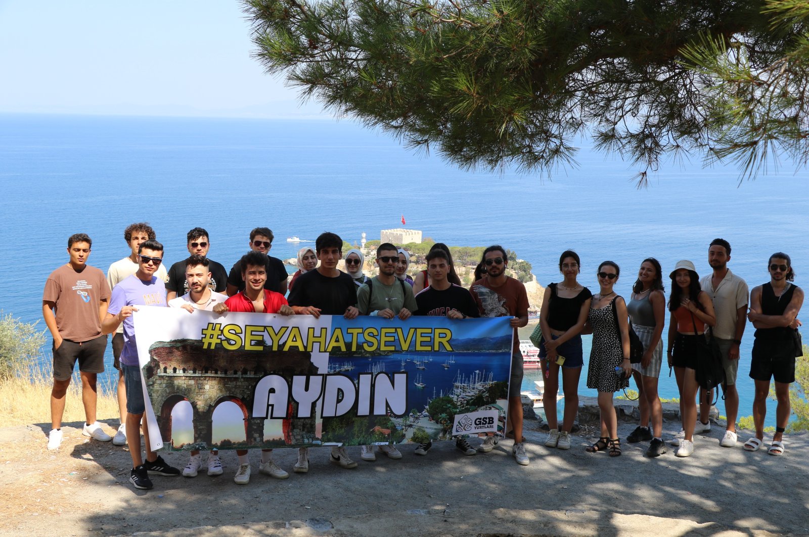 Young travelers staying in a dorm pose with a banner of the program, in Aydın, western Turkey, July 29, 2022. (İHA PHOTO)