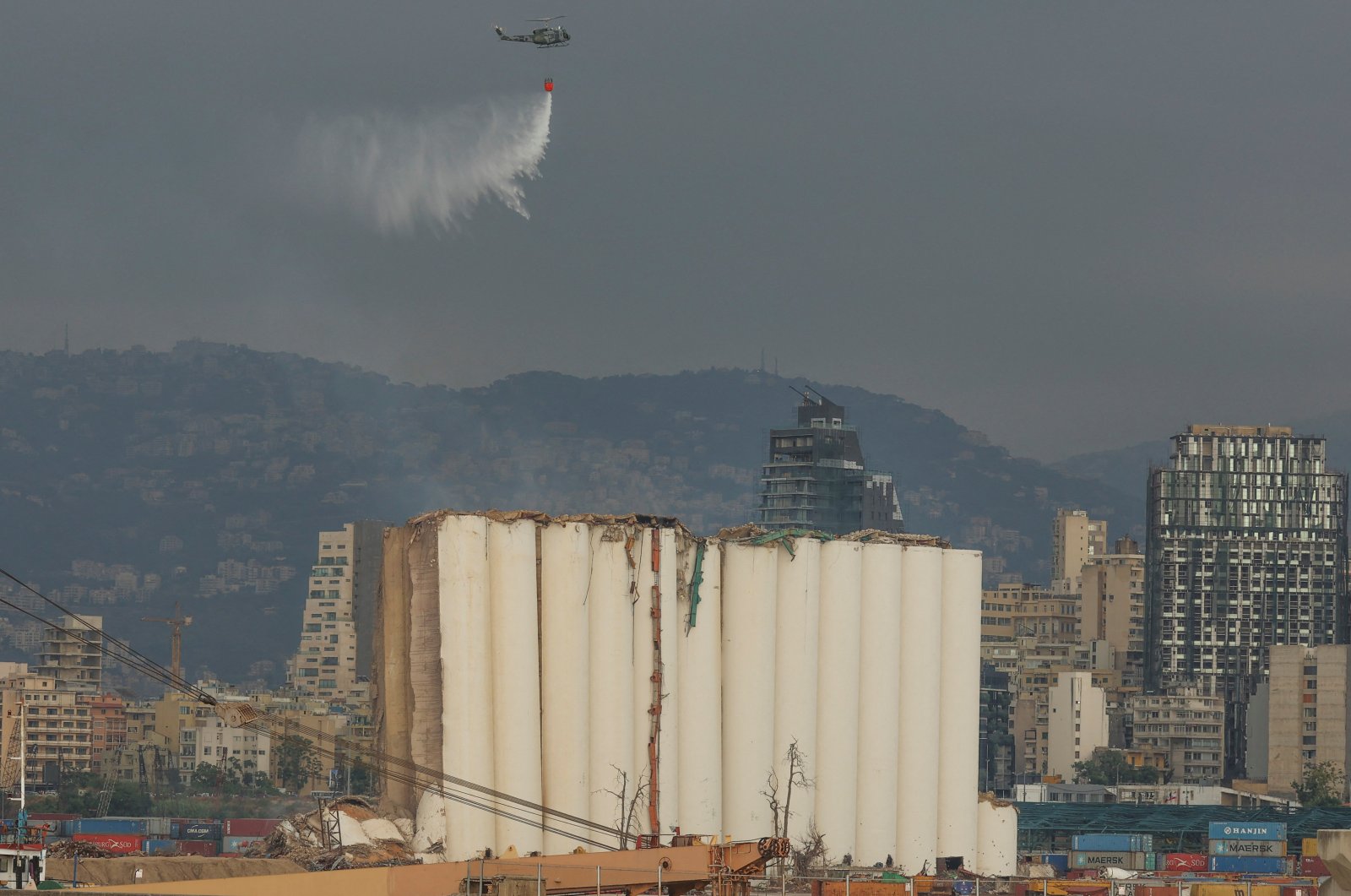 A helicopter drops water over the partially-collapsed Beirut grain silos, damaged in the August 2020 port blast, in Beirut Lebanon July 31, 2022. (Reuters Photo)