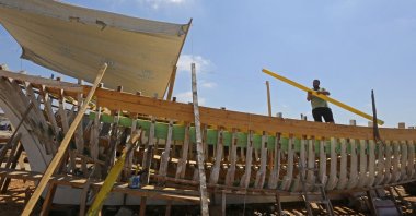 Syrian craftsman Khaled Bahlawan builds a wooden boat at his boatyard in Syria's Mediterranean Island of Arwad on July 24, 2022. (AFP)