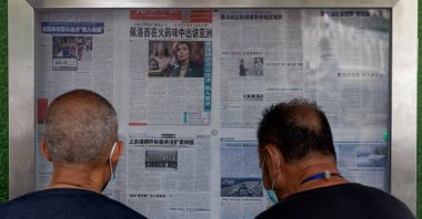 Men read the Global Times newspaper that features a front page article about U.S. House of Representatives Speaker Nancy Pelosi's Asia tour at a street display wall in Beijing, China, Aug. 1, 2022. The front page headline reads: "Pelosi visits Asia in the smell of gunpowder." (Reuters Photo)