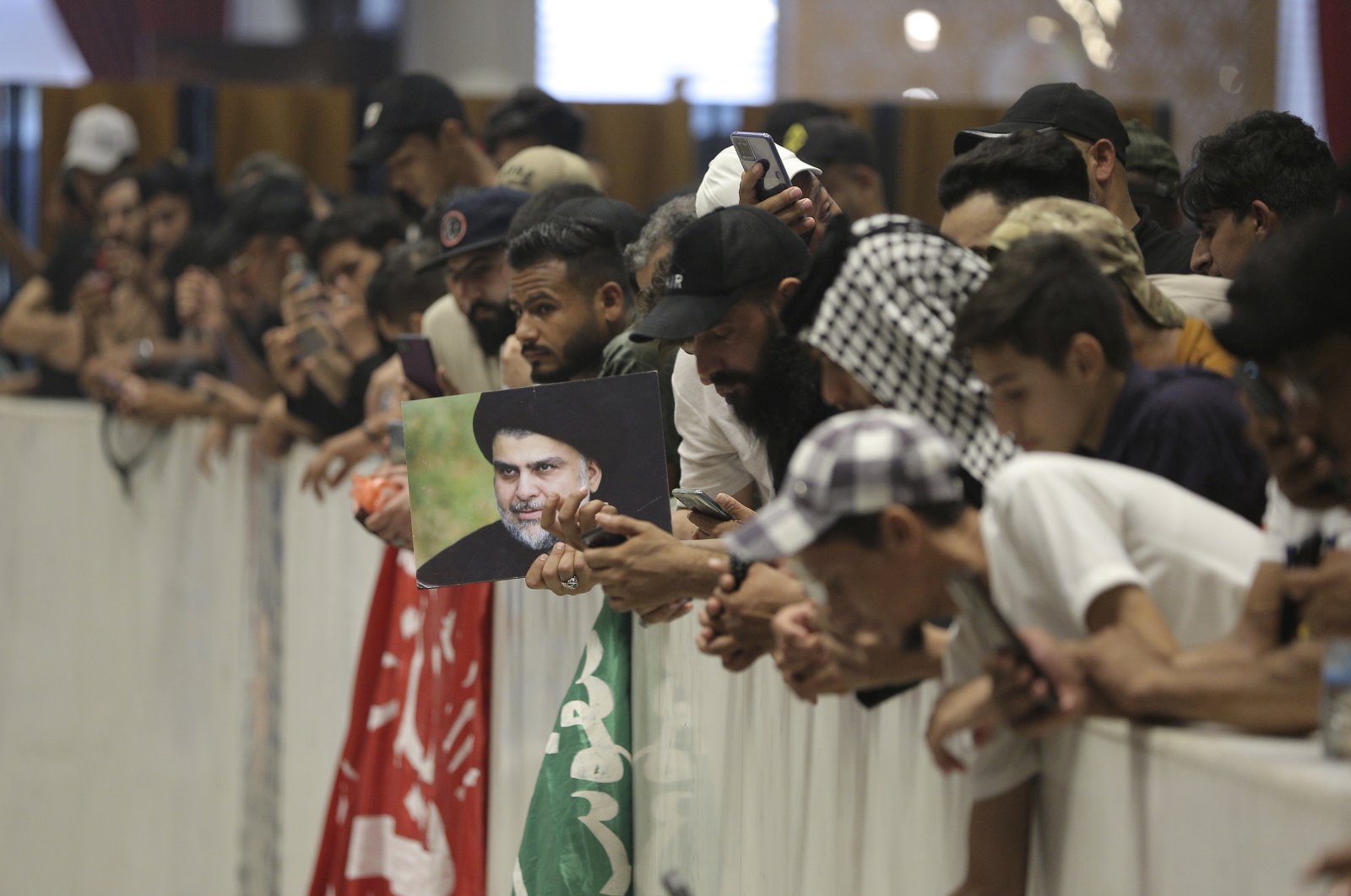 Followers of Shiite cleric Muqtada al-Sadr hold posters with his photo during a sit-in, inside the parliament in Baghdad, Iraq, Aug. 1, 2022. (AP Photo)