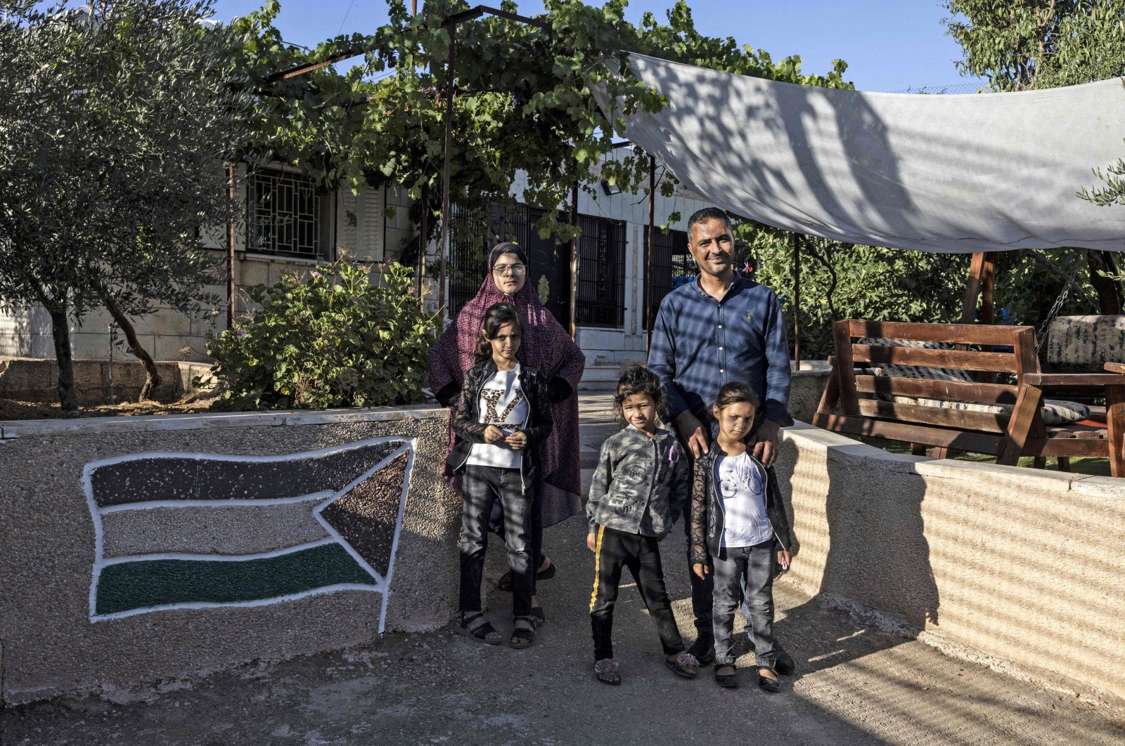 Saadat Sabri Gharib (R) poses with members of his family, in front of his house which is an enclave at the heart of the Jewish settlement of Givon Hahadasha, north of Jerusalem, bordering the West Bank Palestinian village of Beit Ijza, July 19, 2022.(AFP Photo)