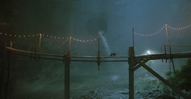 The cat and B12 cross a wooden bridge, in a screenshot from the video game Stray.