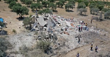 An aerial picture shows Syrians standing around the rubble of a house following a Russian airstrike on the outskirts of the rebel-held city of Jisr al-Shughur in the northwestern province of Idlib, Syria, July 22, 2022. (AFP)
