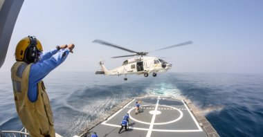 Helicopter deck officer give hand signal to Sikorsky S-70 Sea Hawk helicopter hovering above helicopter deck of Thai Navy ship to receive supplies, Chonburi, Thailand, Jan. 29, 2014. (Shutterstock Photo) 
