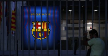 A fan peers through the railings of the entrance of Barcelona&#039;s offices at the Camp Nou stadium in Barcelona, Spain, Aug. 5, 2021. (AP Photo)