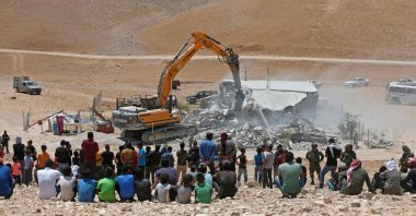Residents watch as an Israeli bulldozer demolishes a Palestinian house in the Umm Qasas area of Masafer Yatta in the occupied West Bank, Palestine, July 25, 2022. (AFP File Photo)