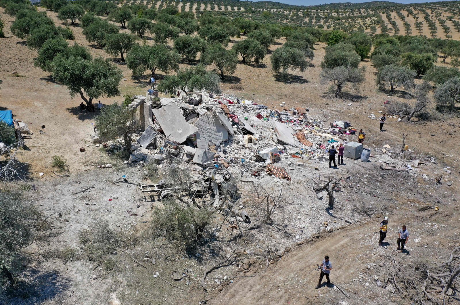 An aerial picture shows Syrians standing around the rubble of a house following a Russian airstrike on the outskirts of the rebel-held city of Jisr al-Shughur in the northwestern province of Idlib, Syria, July 22, 2022. (AFP)