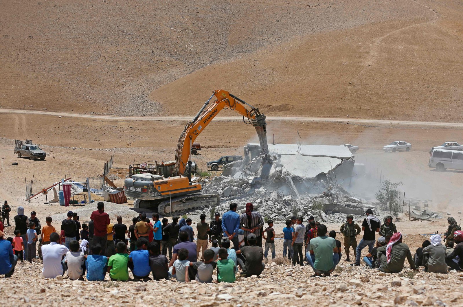 Residents watch as an Israeli bulldozer demolishes a Palestinian house in the Umm Qasas area of Masafer Yatta in the occupied West Bank, Palestine, July 25, 2022. (AFP File Photo)