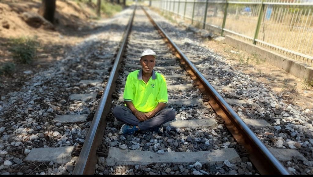 Mehmet Erbil sits on the tracks, in Manisa, western Turkey, Aug. 2, 2022. (PHOTO BY FATMA DAMLA KAYAYERLİ) 