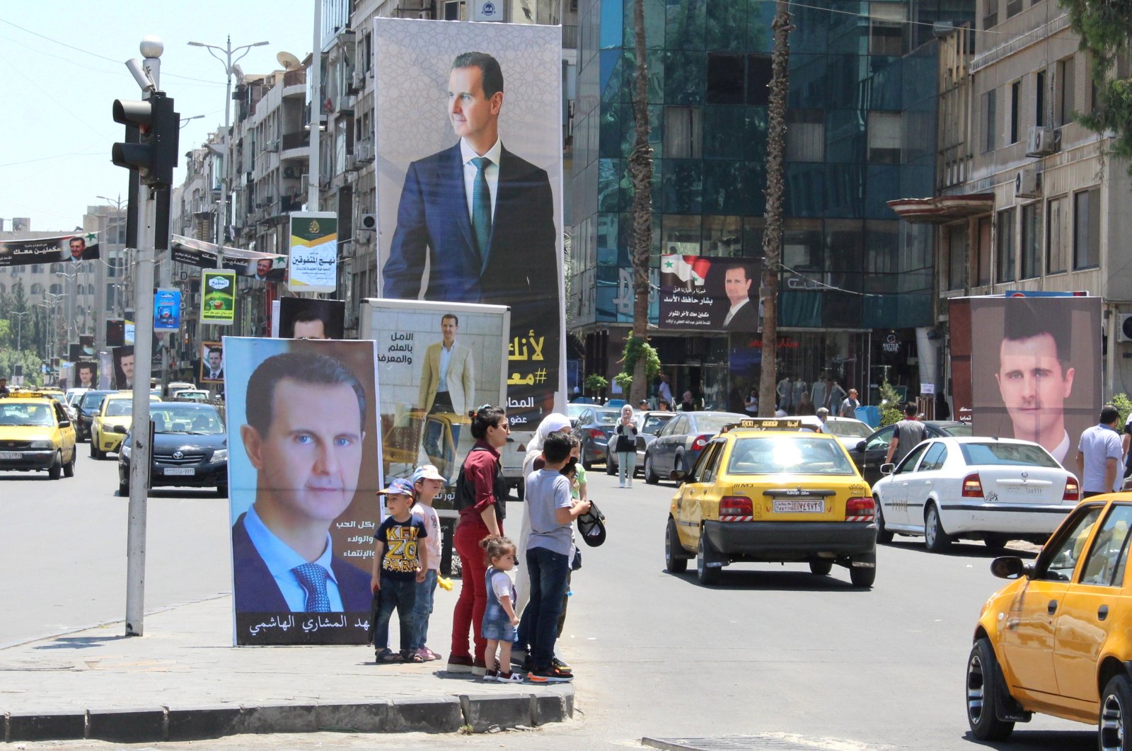 People stand near posters depicting Syria&#039;s President, ahead of the May 26 presidential election, in Damascus, Syria, May 18, 2021. (Reuters File Photo)