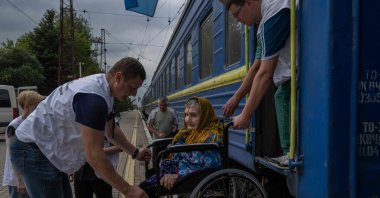 An elderly woman on a wheelchair is helped to board on a train used by "Doctors Without Borders" NGO to evacuate people from Donetsk region, in the train station of Pokrovsk, eastern Ukraine, Aug. 2, 2022. (AFP Photo)