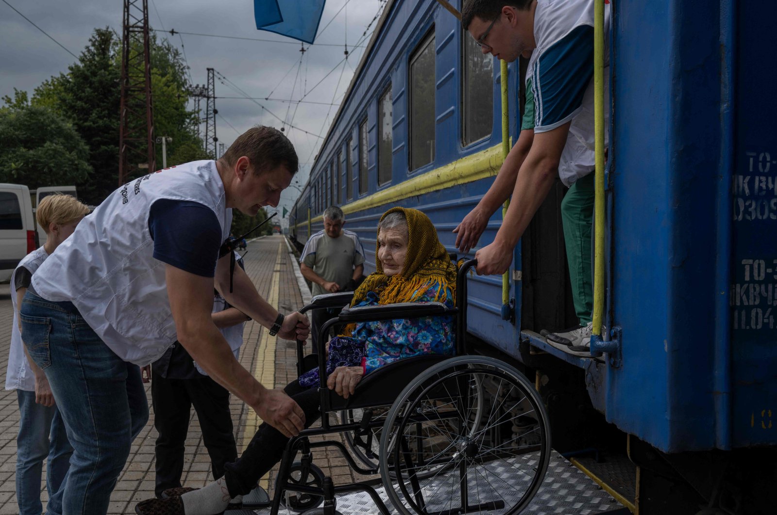 An elderly woman on a wheelchair is helped to board on a train used by &quot;Doctors Without Borders&quot; NGO to evacuate people from Donetsk region, in the train station of Pokrovsk, eastern Ukraine, Aug. 2, 2022. (AFP Photo)