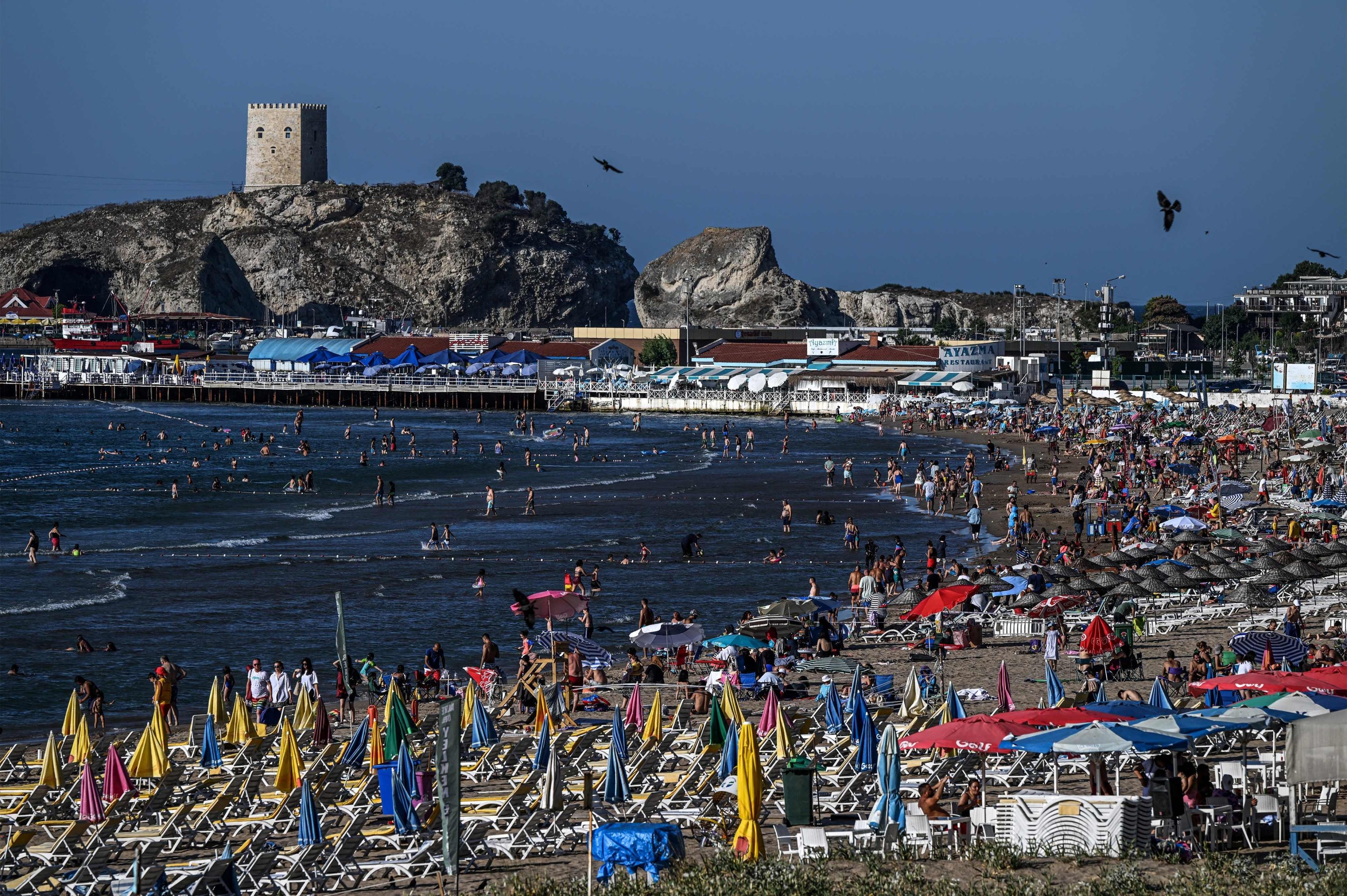 Orang-orang bersantai di pantai di pesisir Laut Hitam di distrik ile, di Istanbul, Turki, 28 Juli 2022. (AFP PHOTO)