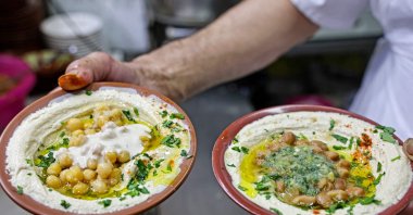 A cook prepares to serve plates of hummus and fava beans to be served to clients at a restaurant in the Old City of Jerusalem, occupied Palestine, July 26, 2022. (AFP Photo)